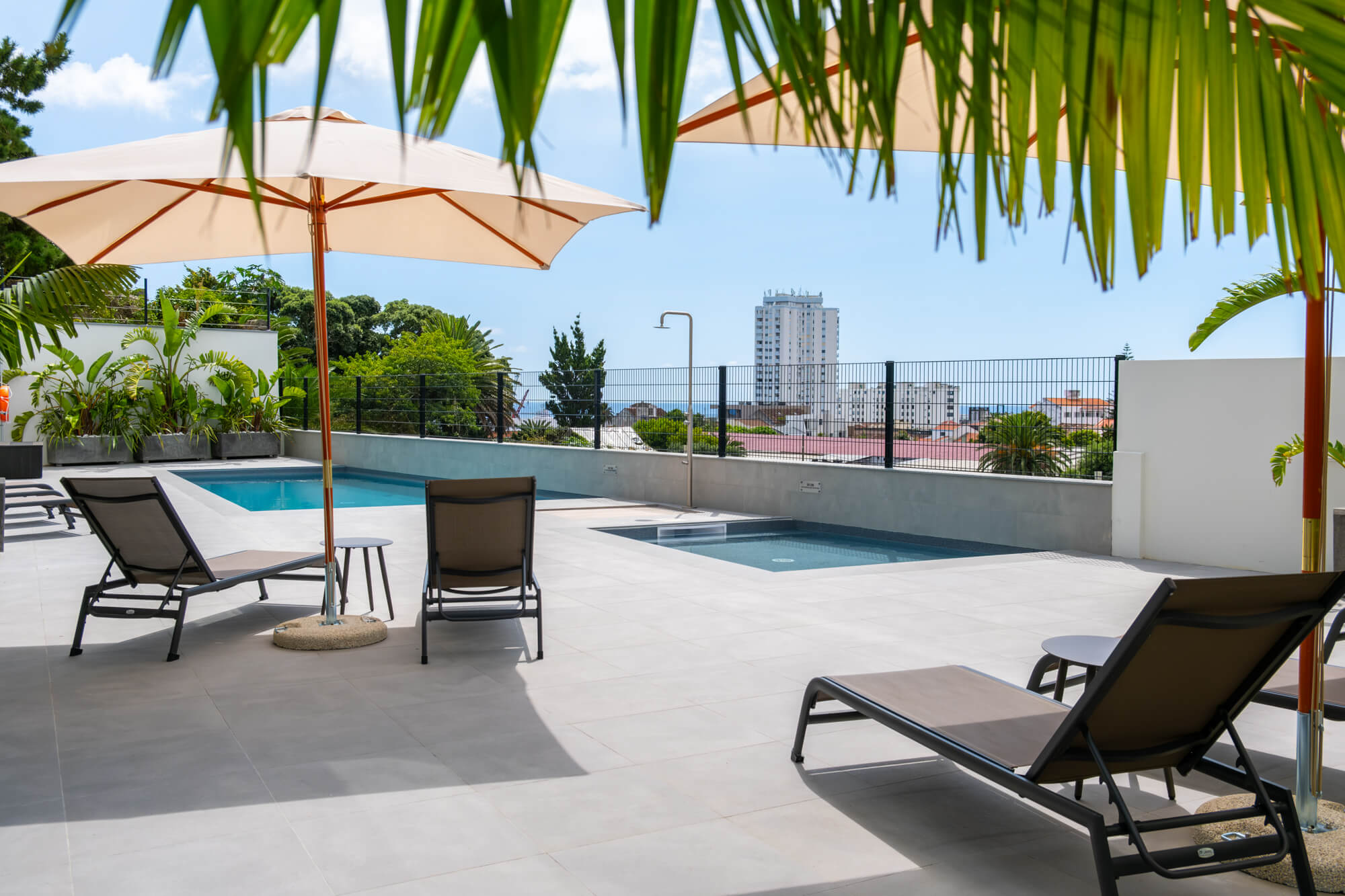 Terraço com piscina, espreguiçadeiras e vista sobre a cidade de Ponta Delgada